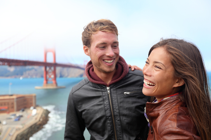 Happy young couple laughing in San Francisco by Golden Gate Bridge. Interracial young modern couple, Asian woman, Caucasian man. Click on the banners for more: